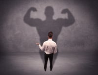 A young salesman standing with his back, looking at his musculous shadow reflecting on the wall concept